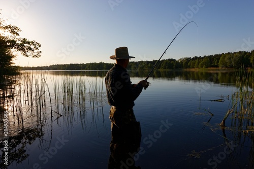 Fisherman standing in the lake and catching the fish on sunny day