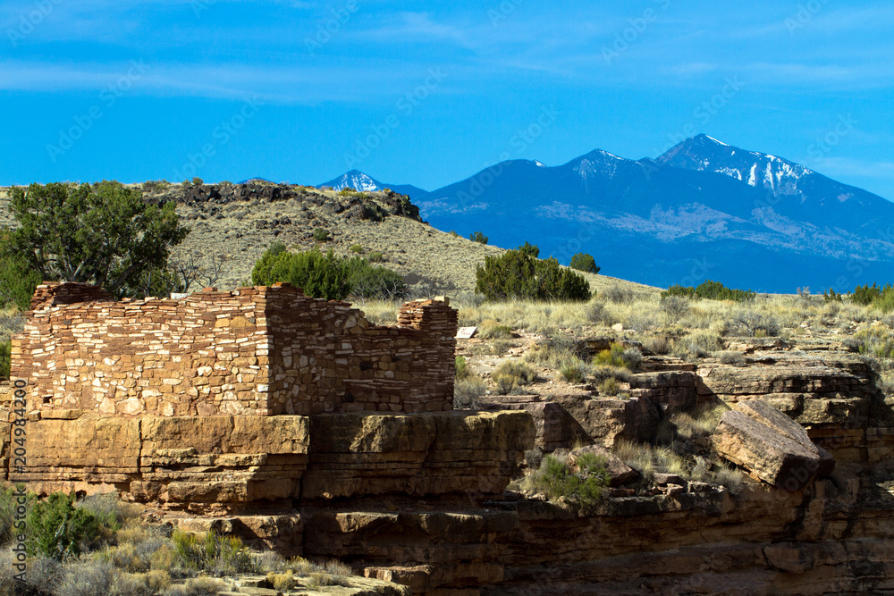 The Box Canyon ruin inside Wupatki National Monument in northern Arizona protects an ancient Native American pueblo site. This image shows the San Francisco Peaks in the background