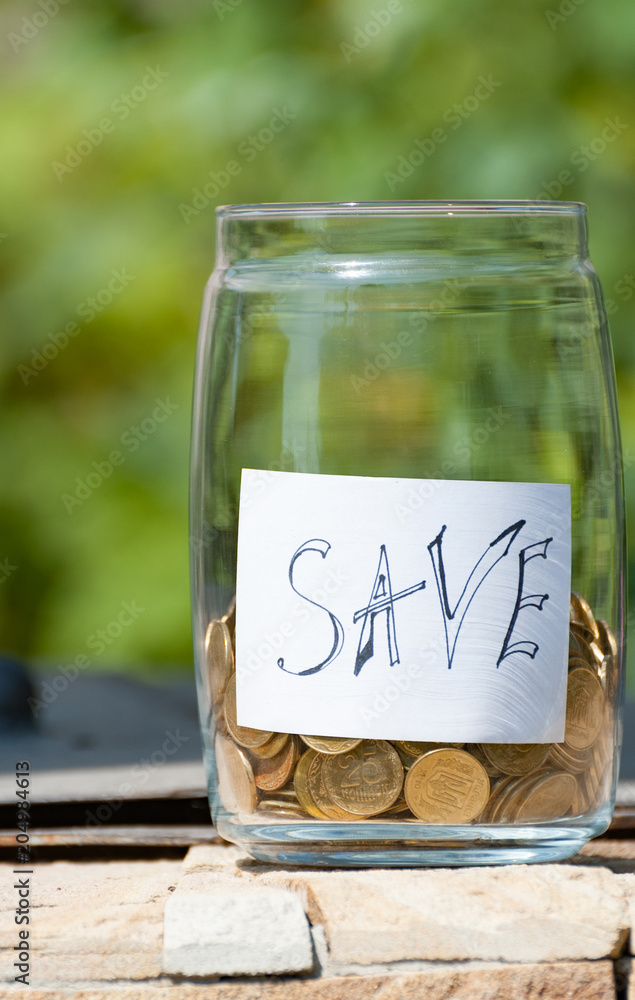 Bottle with coins and with an inscription saving the text on a neutral background. Vertical view Bottle with coins and with an inscription saving the text on a neutral background. Vertical view