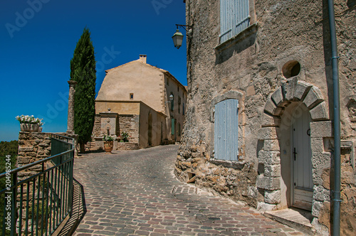 View of typical stone houses with sunny blue sky, in an alley of the historical village of Menerbes. Located in the Vaucluse department, Provence-Alpes-Côte d'Azur region, southeastern France