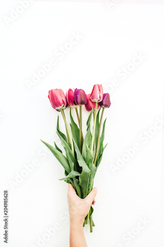 Woman hand holding tulips bouquet on white. Flat lay, top view flowers festive background. © Floral Deco