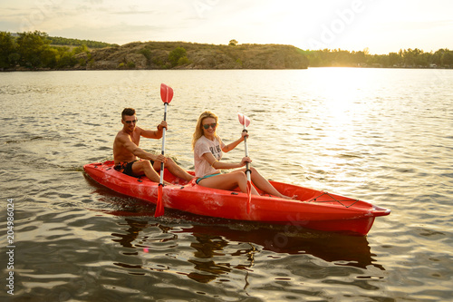 Young Couple Paddling Kayak on Beautiful River or Lake in the Evening at Sunset