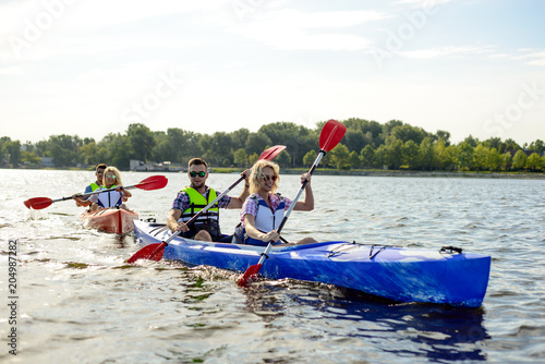 Friends Paddling Kayaks on Beautiful River or Lake