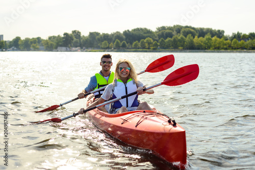 Young Happy Couple Paddling Kayak on Beautiful River or Lake © Maksym Protsenko
