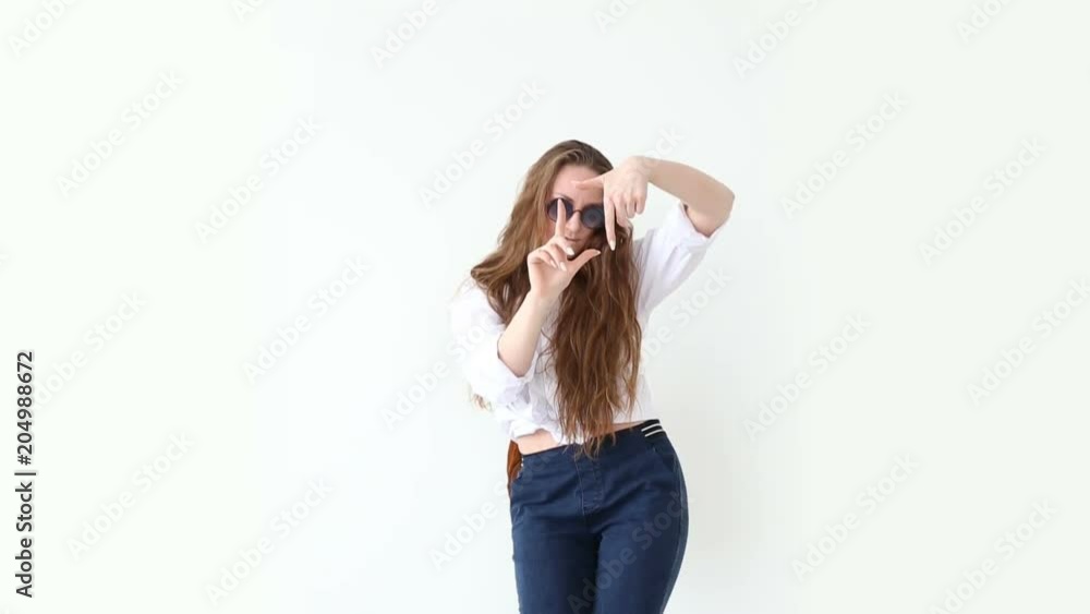 fashion of modern youth. stylish girl posing against white wall in jeans, white shirt, with leather backpack and glasses. fashion of modern youth. stylish girl posing against white wall in jeans, white shirt, with leather backpack and glasses.