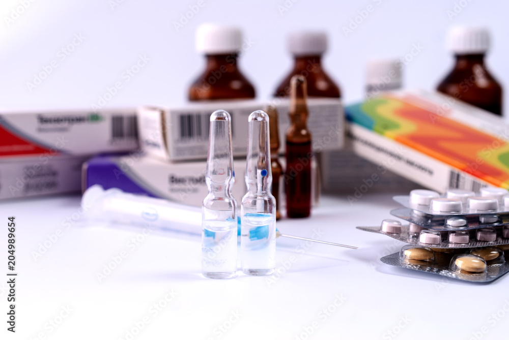 Syringe, ampoules and medical preparations on white table Syringe, ampoules and medical preparations on white table