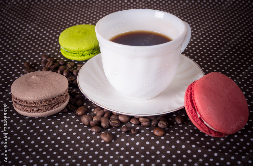 White cup, crocked on coffee beans scattered on the table White cup, crocked on coffee beans scattered on the table