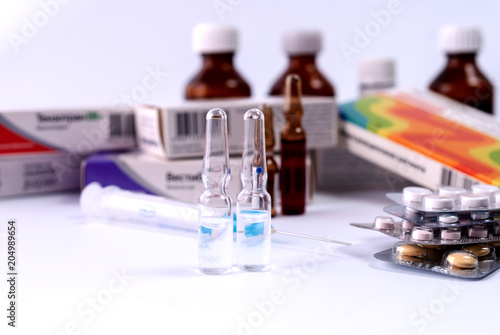 Syringe, ampoules and medical preparations on white table