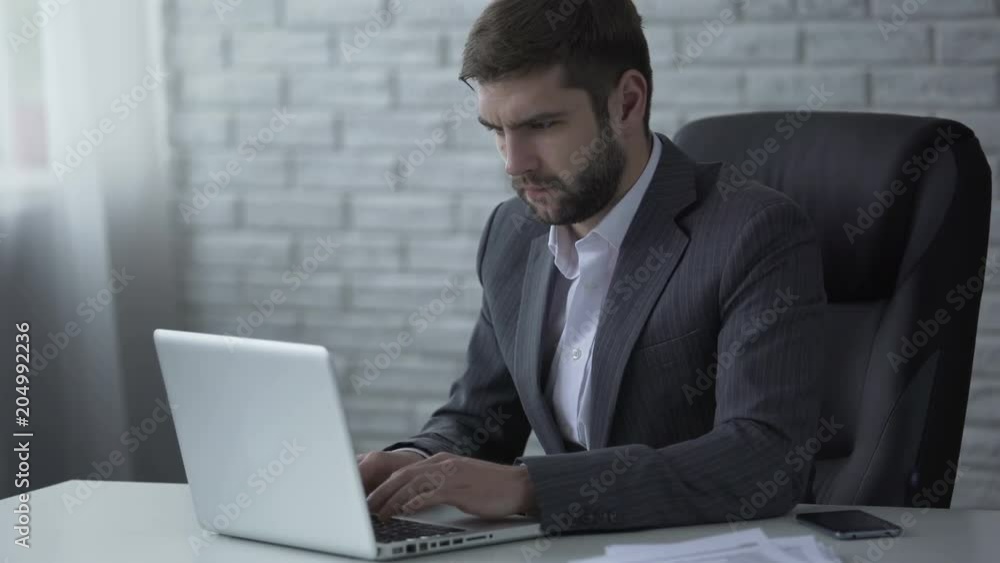 Agitated businessman nervously typing on laptop, worrying about startup success Agitated businessman nervously typing on laptop, worrying about startup success