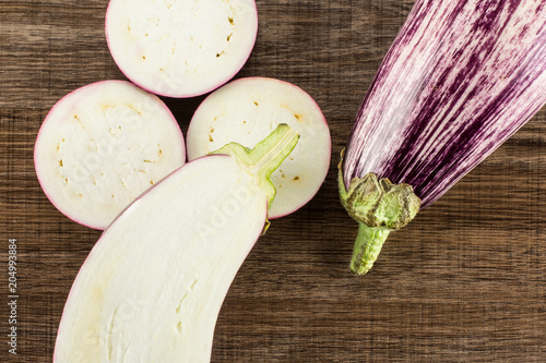 Striped purple eggplants set top view isolated on brown wood background whole one half and sliced three rings. photo