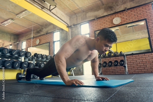 Young athletic man doing push-ups in the gym