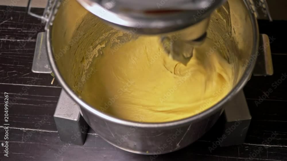 Mixing a dough for bread baking with professional kneader spiral machine at the manufacturing. The dough is kneaded for burgers. Very luscious lush air bun. Mixing a dough for bread baking with professional kneader spiral machine at the manufacturing. The dough is kneaded for burgers. Very luscious lush air bun.