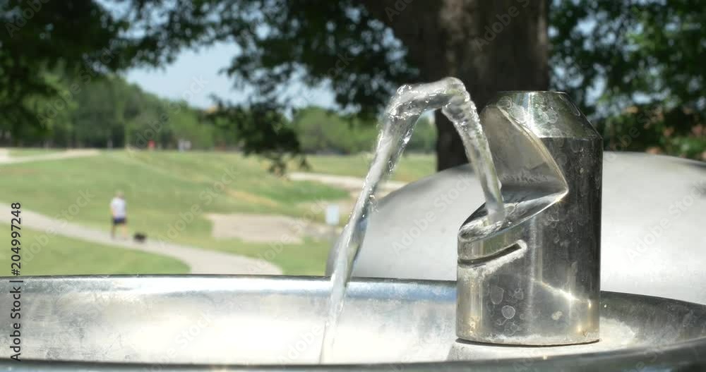 Drinking fountain in a park with people in background. Drinking fountain in a park with people in background.