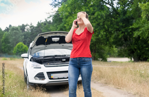 Stressed young woman with broken car on countryside road calling car service © Кирилл Рыжов