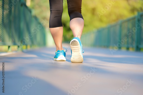 young fitness woman legs walking in the park outdoor, female runner running on the road outside, asian girl jogging and exercise on footpath in sunlight morning. healthcare and well being concepts