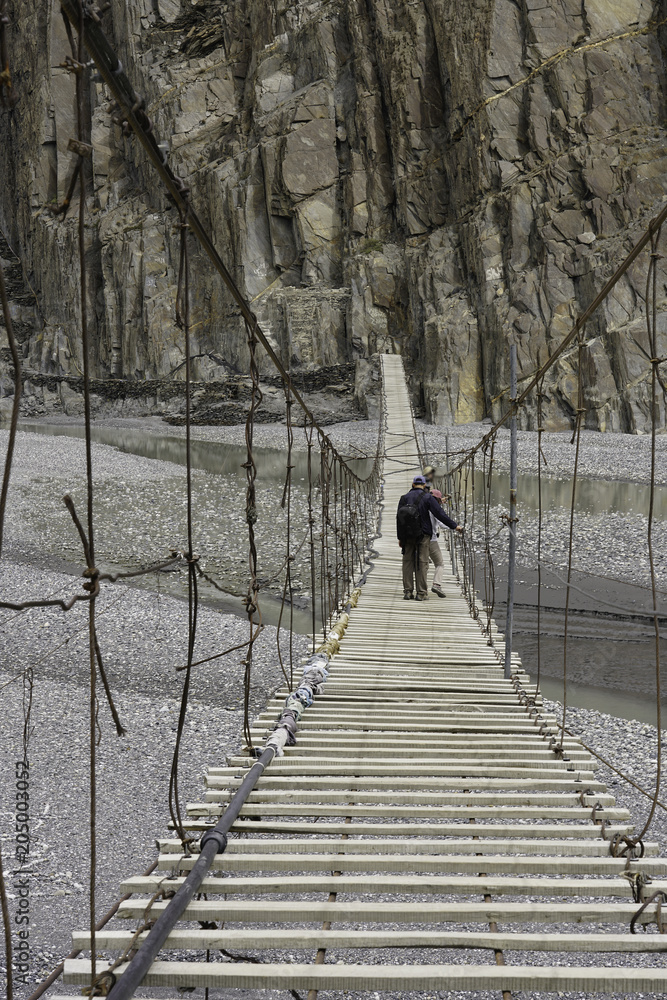 Tourists walking across suspension bridge ,Hunza Valley, Gilgit, Balistan, Pakistan