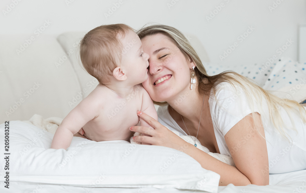 Portrait of happy smiling young mother lying with her baby son on bi bed Portrait of happy smiling young mother lying with her baby son on bi bed