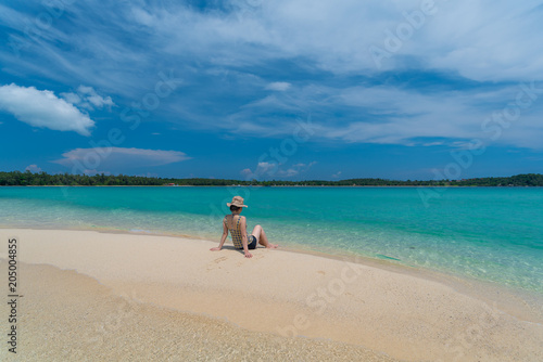 A Asian woman relaxing on beautiful beach Koh Kham island ,Trad,Thailand with blue cloud sky background