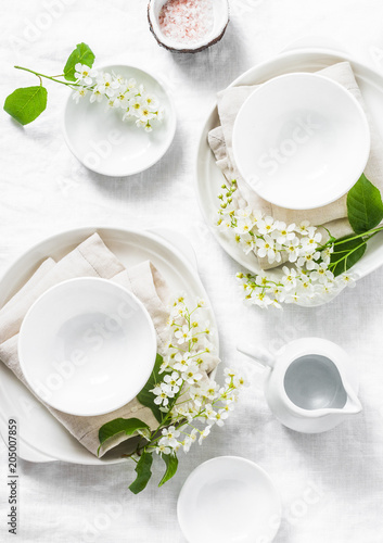Served empty table with white crockery, flowers, napkins on white background, top view. Cozy home serving food table concept