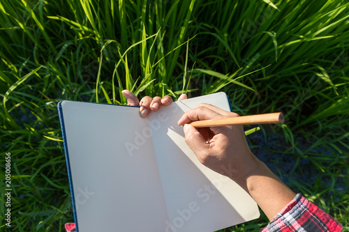 Woman hand holding a pencil on a notebook. Concept for agriculture