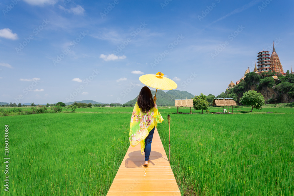 Holidays travel concept,young Women holding umbrellas Nature trails walking on a wooden bridge with green rice field Holidays travel concept,young Women holding umbrellas Nature trails walking on a wooden bridge with green rice field
