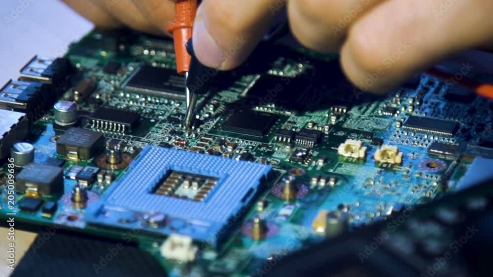 electronic renovation in repair shop. technician testing electric current in the motherboard using multimeter electronic renovation in repair shop. technician testing electric current in the motherboard using multimeter
