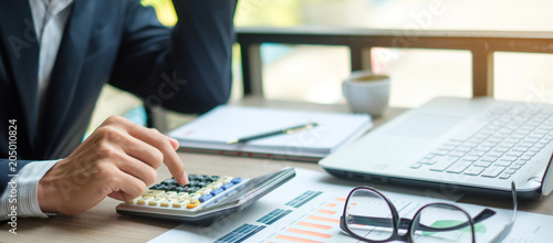 Businessman using calculator for analysis maketing plan, Accountant calculate financial report, computer with graph chart.  Business, Finance and Accounting concepts photo