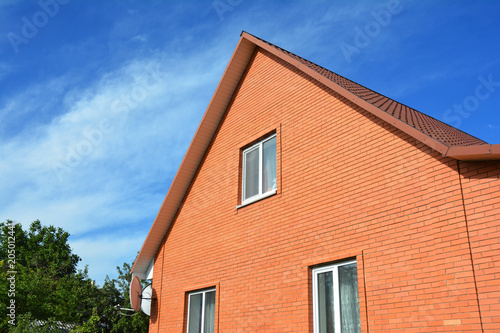 Modern red brick house construction. Brick house facade building with metal roof. © bildlove