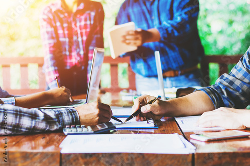 business partners hands using pen over document with their colleagues working on background