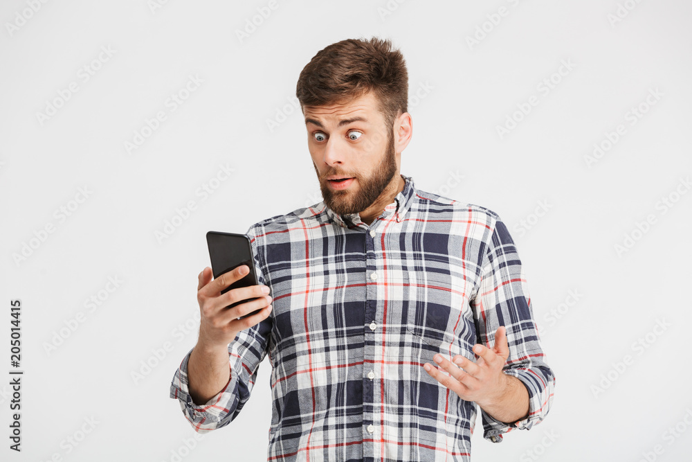 Portrait of a confused young man looking at mobile phone Portrait of a confused young man looking at mobile phone