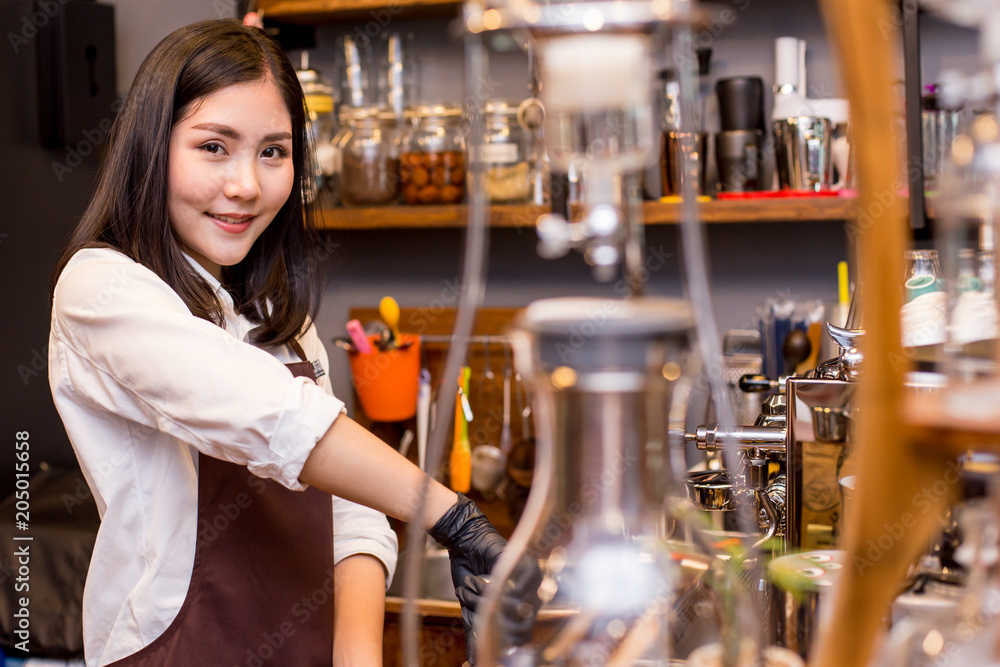 Asian women Barista smiling and looking to camera in coffee shop counter.  Barista female working at cafe. Working woman small business owner or sme concept.