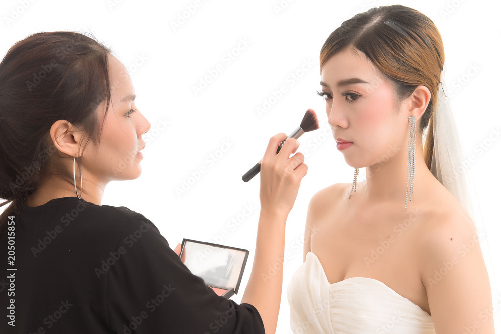 Close up makeup artist preparing asian beautiful bride before the wedding in a morning on white background. Close up makeup artist preparing asian beautiful bride before the wedding in a morning on white background.