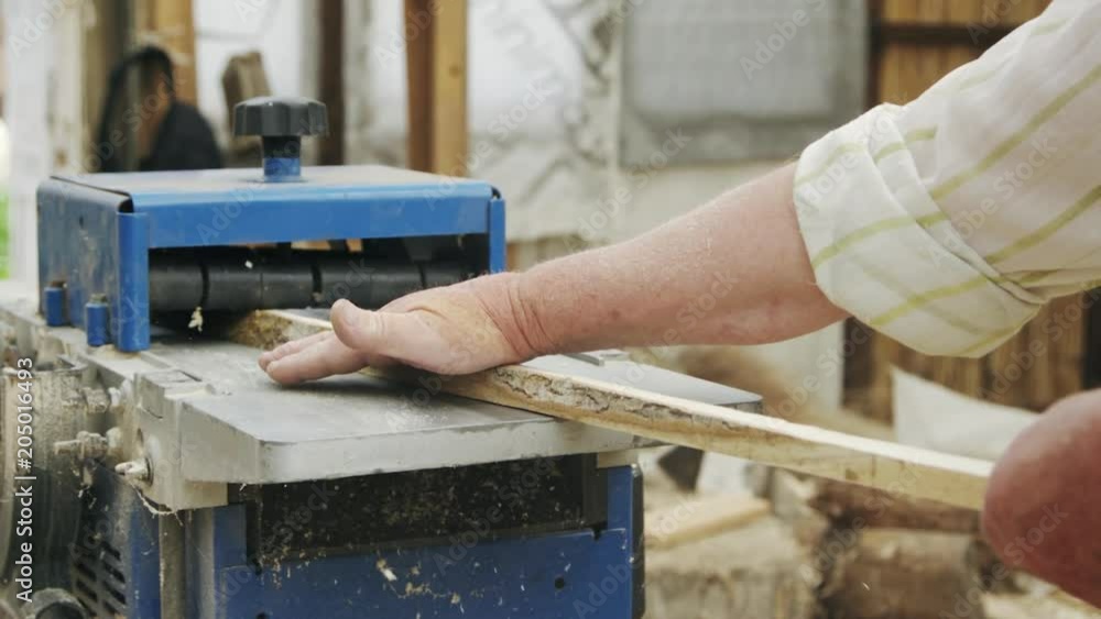 Slow motion shot of elderly man carpenter builds a small boat with his hands out of wood in a small workshop Slow motion shot of elderly man carpenter builds a small boat with his hands out of wood in a small workshop