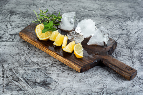 cocktail ingredient: Summer mint and lemon for refreshing cocktail mojito with ice on kitchen board. photo