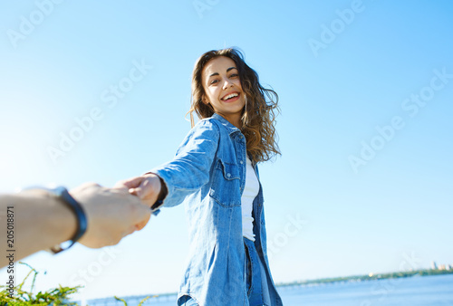 Obraz na plátně portrait of a young smiling attractive woman in jeans clothes at sunny day on the blue sky background