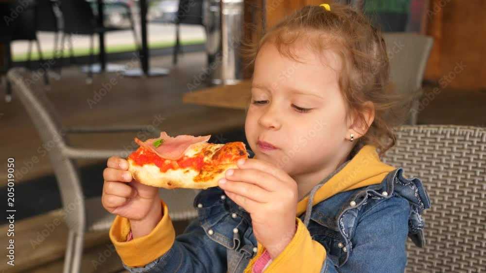 Hungry little girl - child eating a piece of pizza with mozzarella and prosciutto Hungry little girl - child eating a piece of pizza with mozzarella and prosciutto