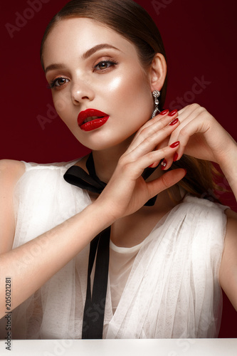 Beautiful girl in white dress with classic make-up and red manicure. Beauty face. Photo taken in the studio.