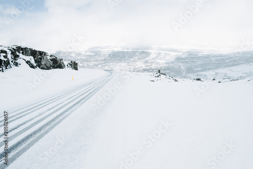 Tire prints on snow and black snow-covered rocks. Snow texture minimalistic background