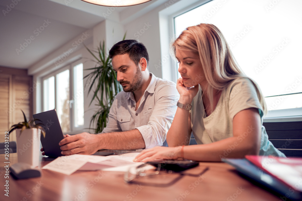 Young couple calculating bills at home Young couple calculating bills at home