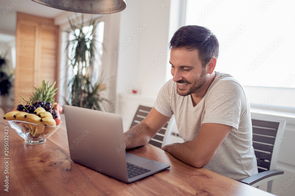 Happy young man doing banking with his laptop Happy young man doing banking with his laptop