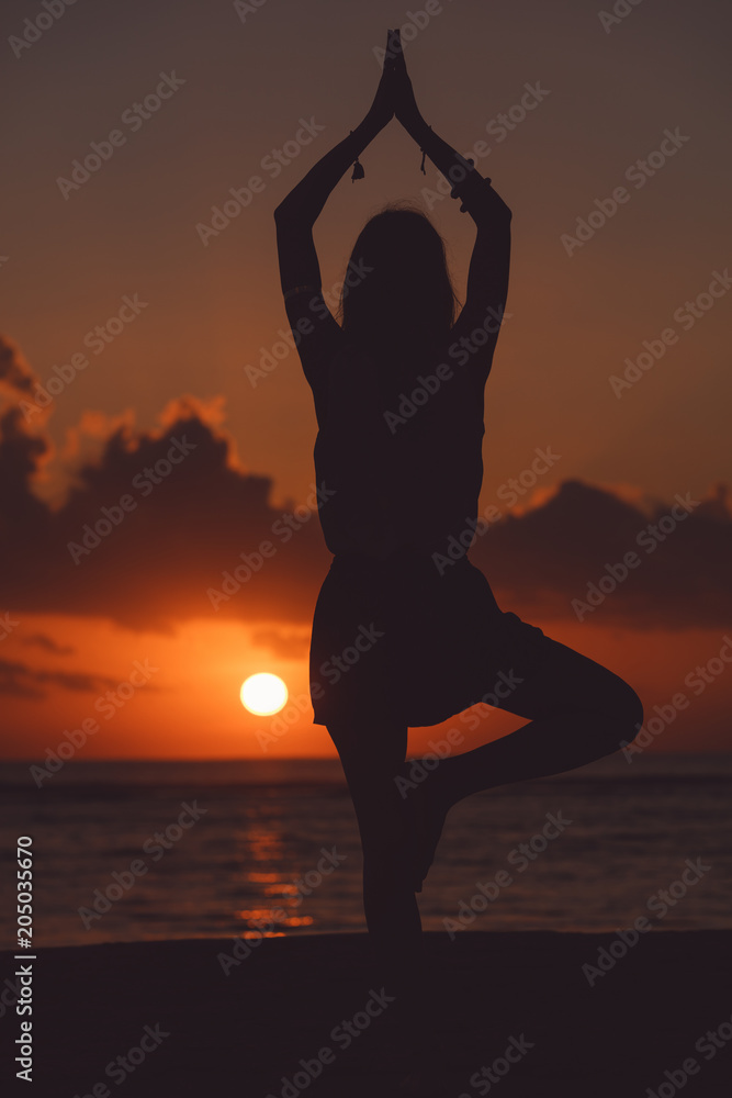 Young woman practicing yoga on the beach.