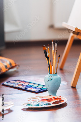 Artist paint brushes and palette on wooden background. Vertical photo