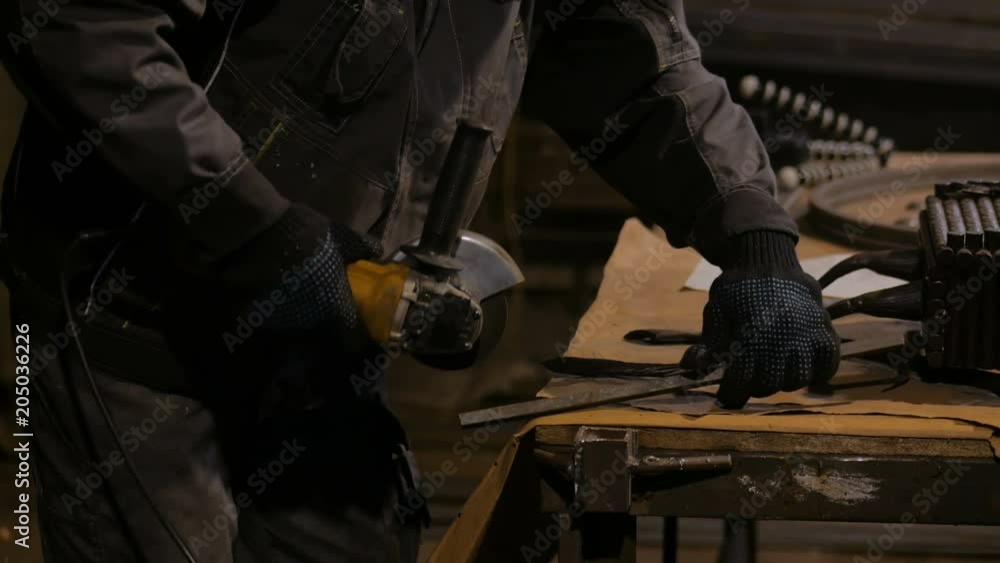 Professional blacksmith sawing metal with hand circular saw at forge, workshop. Handmade, craftsmanship and blacksmithing concept Professional blacksmith sawing metal with hand circular saw at forge, workshop. Handmade, craftsmanship and blacksmithing concept
