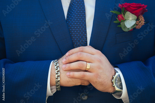 Handsome confident groom putting on watch in suit closeup black and whitebusiness suit of the groom with a watch, a tie and a buttonhole photo