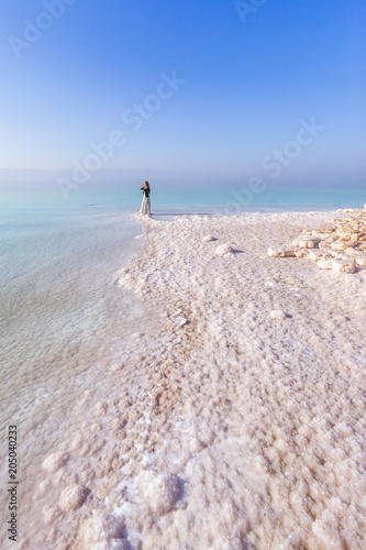 Blonde young woman in a long skirt on the shore of the dead sea. Jordan