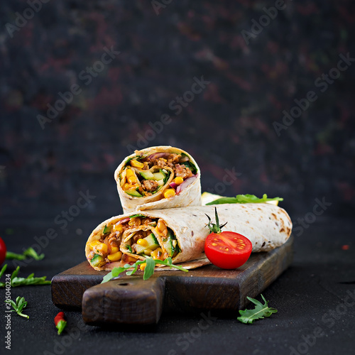 Burritos wraps with beef and vegetables on  black background. Beef burrito, mexican food.