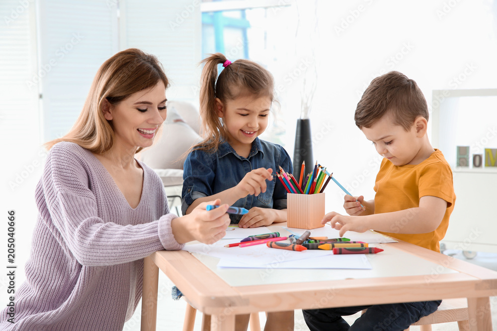 Cute little children and their nanny drawing at home Cute little children and their nanny drawing at home