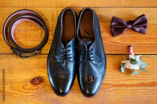 wedding details. men's brown wedding shoes, belt, boutonniere on the floor