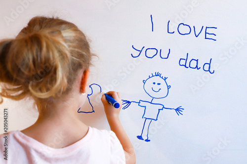 Little girl draws  family with marker on a white board.