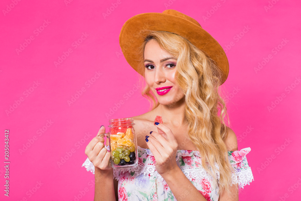 Young beautiful woman with fruit jar on pink background
